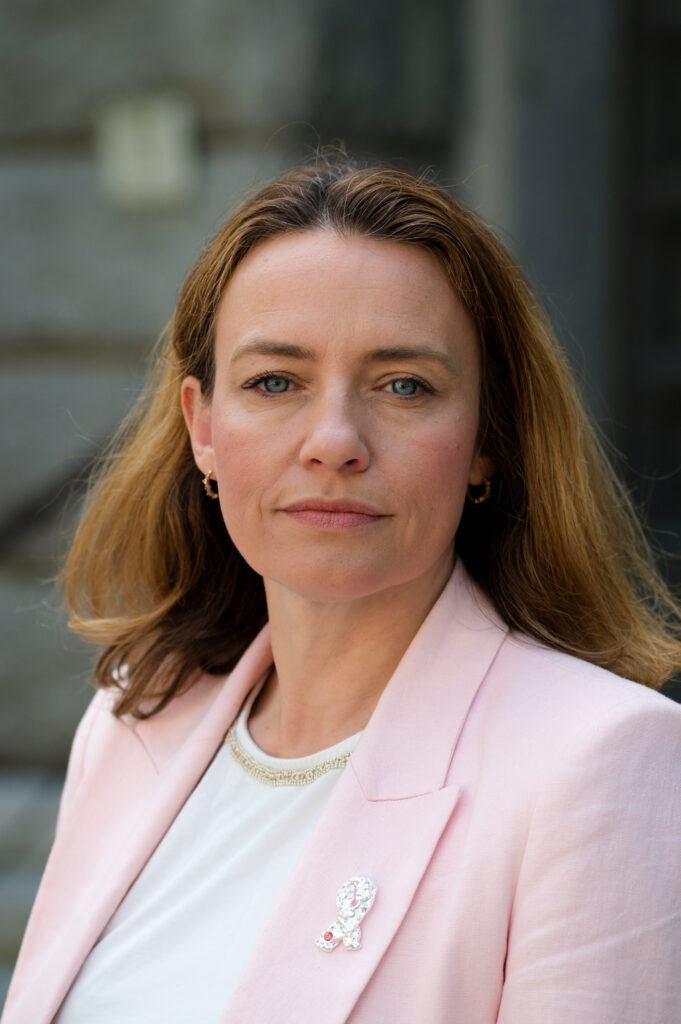 Kreftforeningens generalsekretær Ingrid Stenstadvold Ross ser i kamera med skurrete bakgrunn.