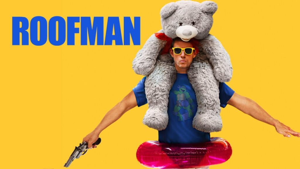 En mann med gule solbriller og blå t-skjorte sitter med en stor grå bamse på skuldrene og holder en lekepistol mot en gul bakgrunn med ordet "ROOFMAN".