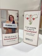 På et hvitt bord ligger to informasjonsbrosjyrer på norsk om screening for livmorhalskreft, den ene med en kvinne som holder et skilt, den andre med en medisinsk illustrasjon.