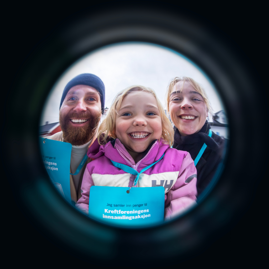 En småbarnsfamilie, mor, far og datter, som smiler til kamera og holder opp Innsamlingsaksjonens innsamlingsmateriell. 