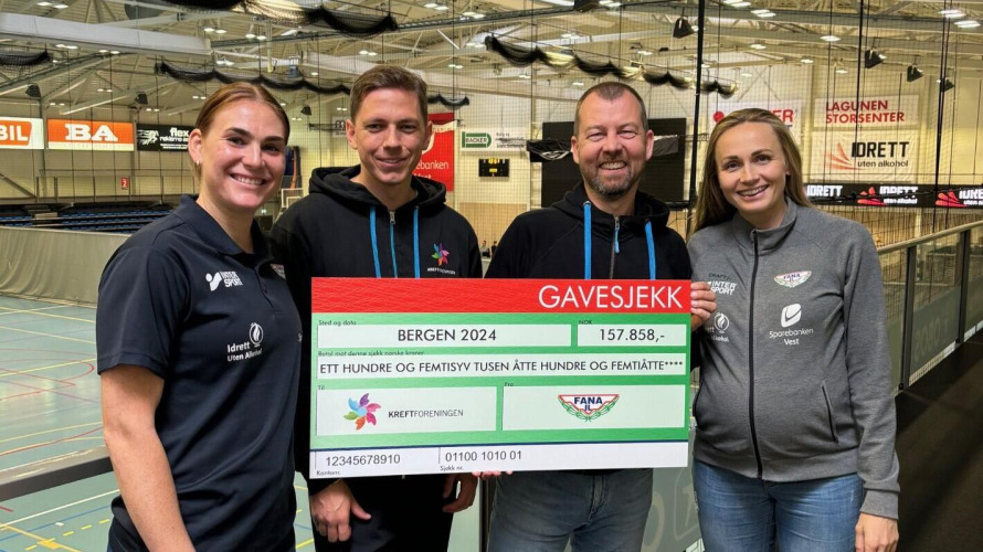Fire personer står innendørs med en stor seremoniell sjekk på 157 858 kroner fra Fana IL, med en idrettshall synlig i bakgrunnen.