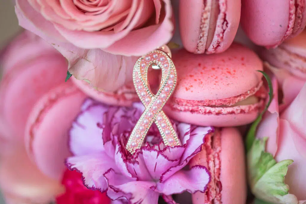 En rosa sløyfe på rosa makroner, roser og en nellike, som symboliserer oppmerksomhet rundt brystkreft.